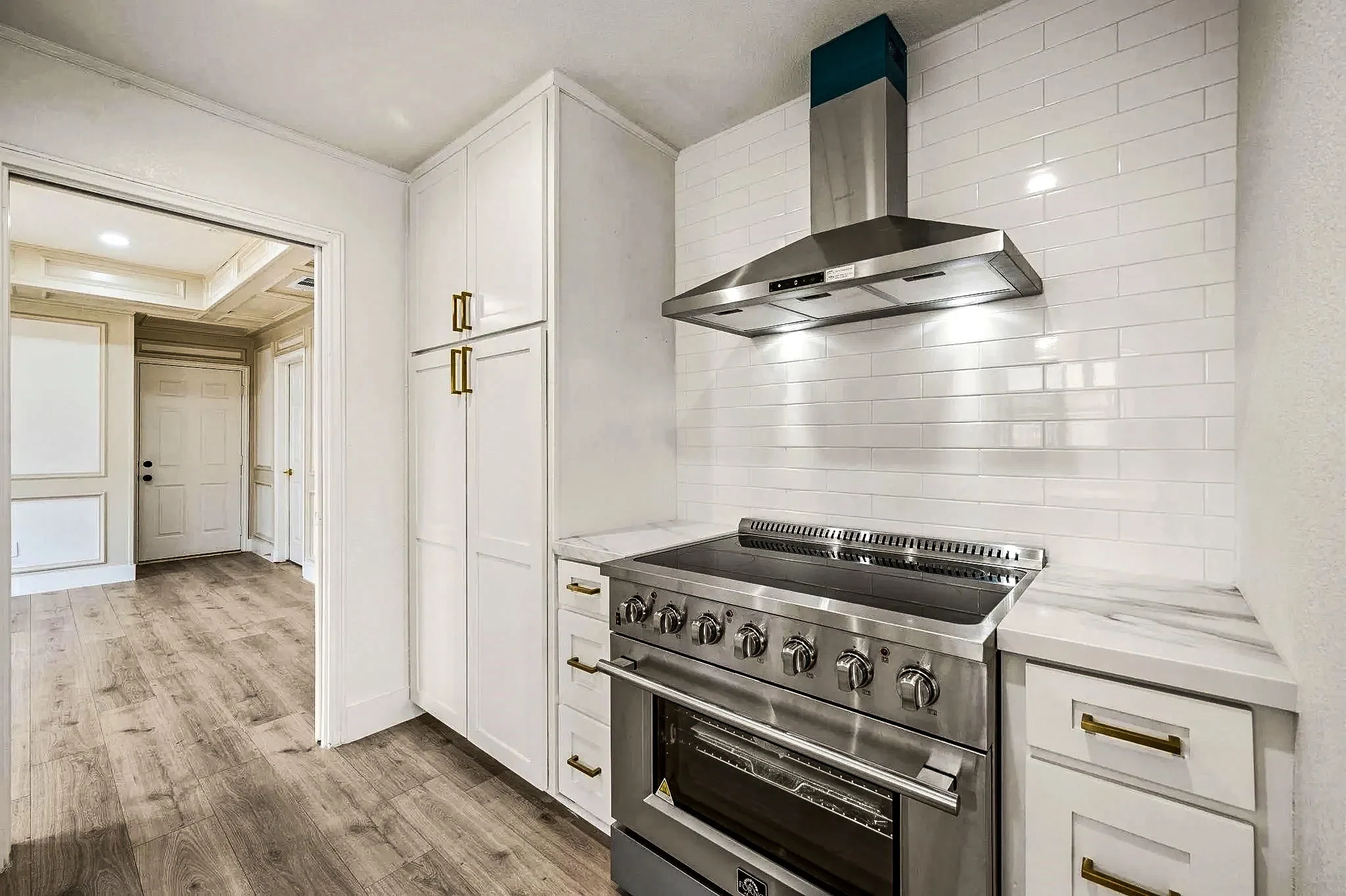 White kitchen with a professional range, marble-look backsplash and brass hardware in a completed Grapevine, Texas whole-home remodel.