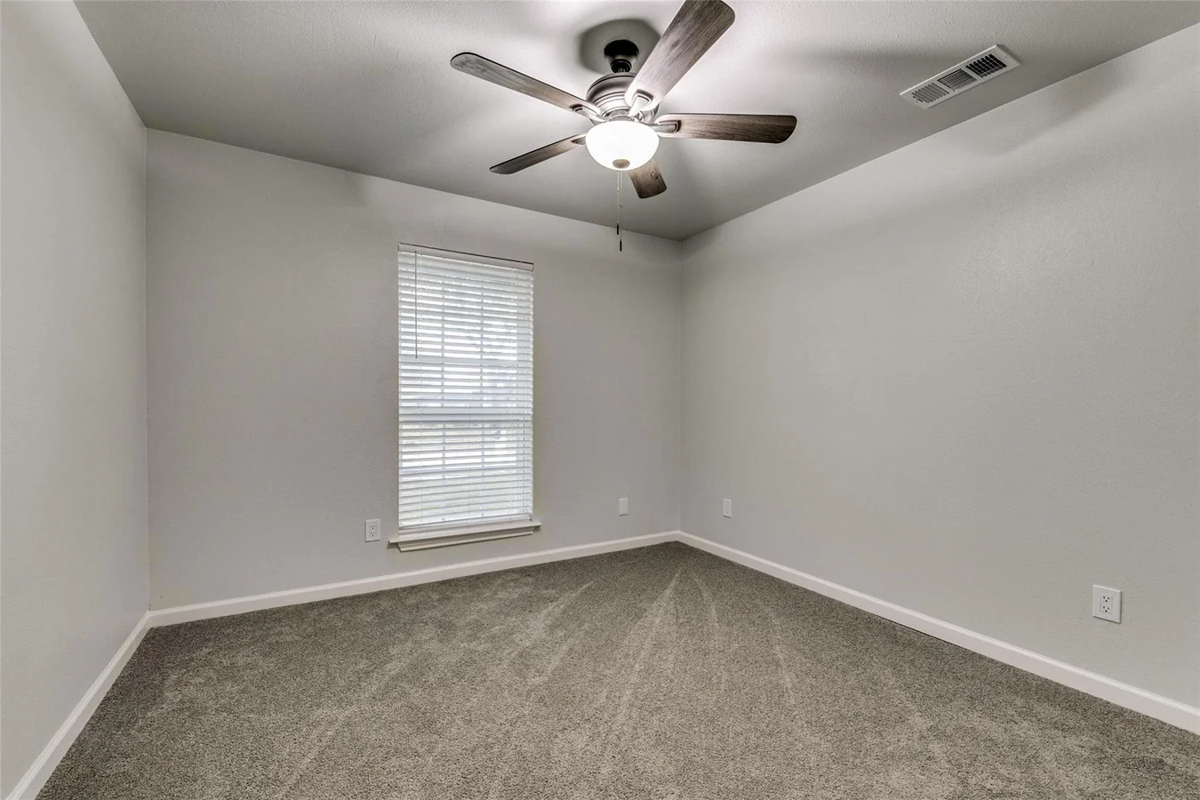 Secondary bedroom with new gray carpet, light gray walls, two windows, white trim, and ceiling fan in Plano, Texas.