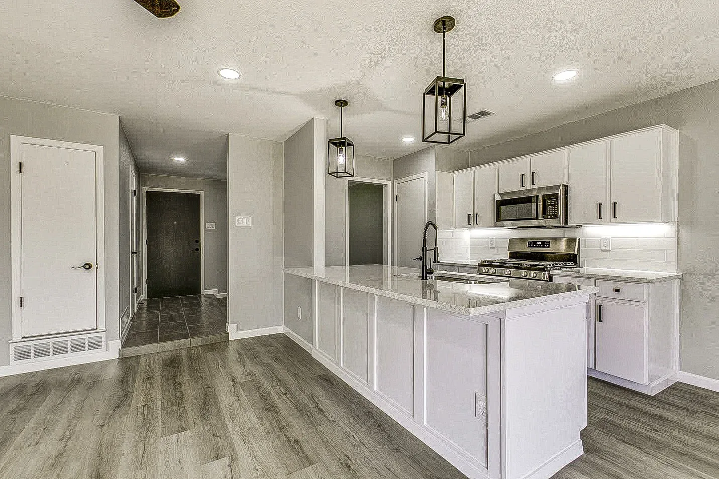 White custom kitchen with island, shaker cabinetry, and integrated lighting