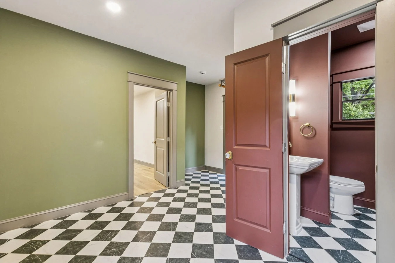 Green laundry and powder room with a black-and-white checkerboard floor, sliding barn door, and pedestal sink in Bishop Arts, Dallas, Texas.
