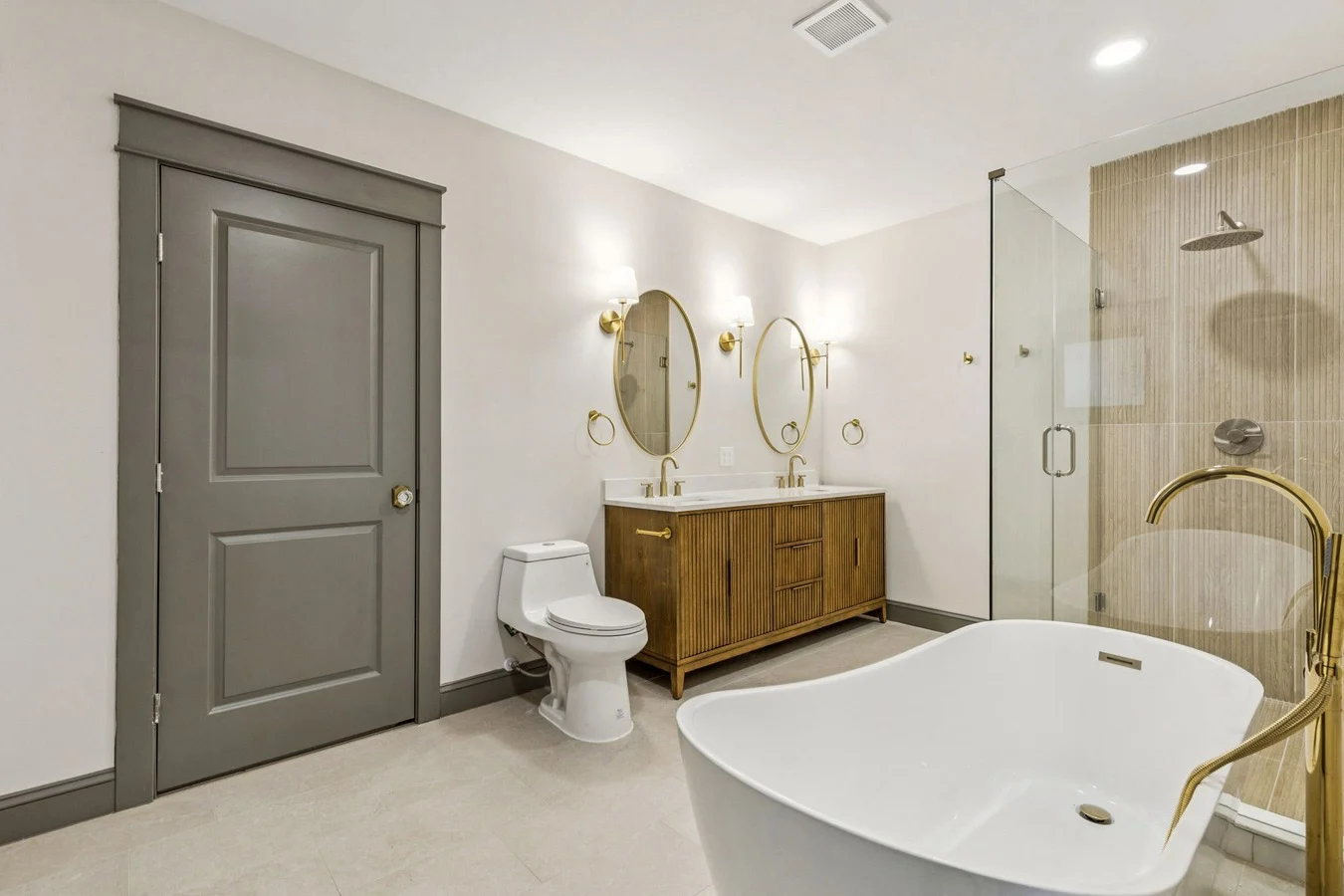 Primary bathroom addition with a freestanding tub, glass shower, wood double vanity, and brushed brass fixtures in Bishop Arts, Dallas, Texas.