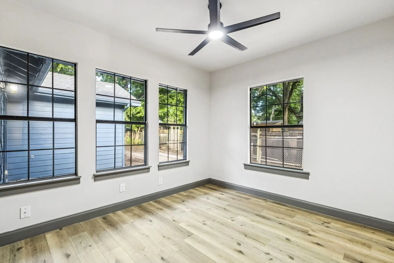 Secondary bedroom with black-framed windows, light wood-look flooring, white walls, and charcoal trim in Bishop Arts, Dallas, Texas.