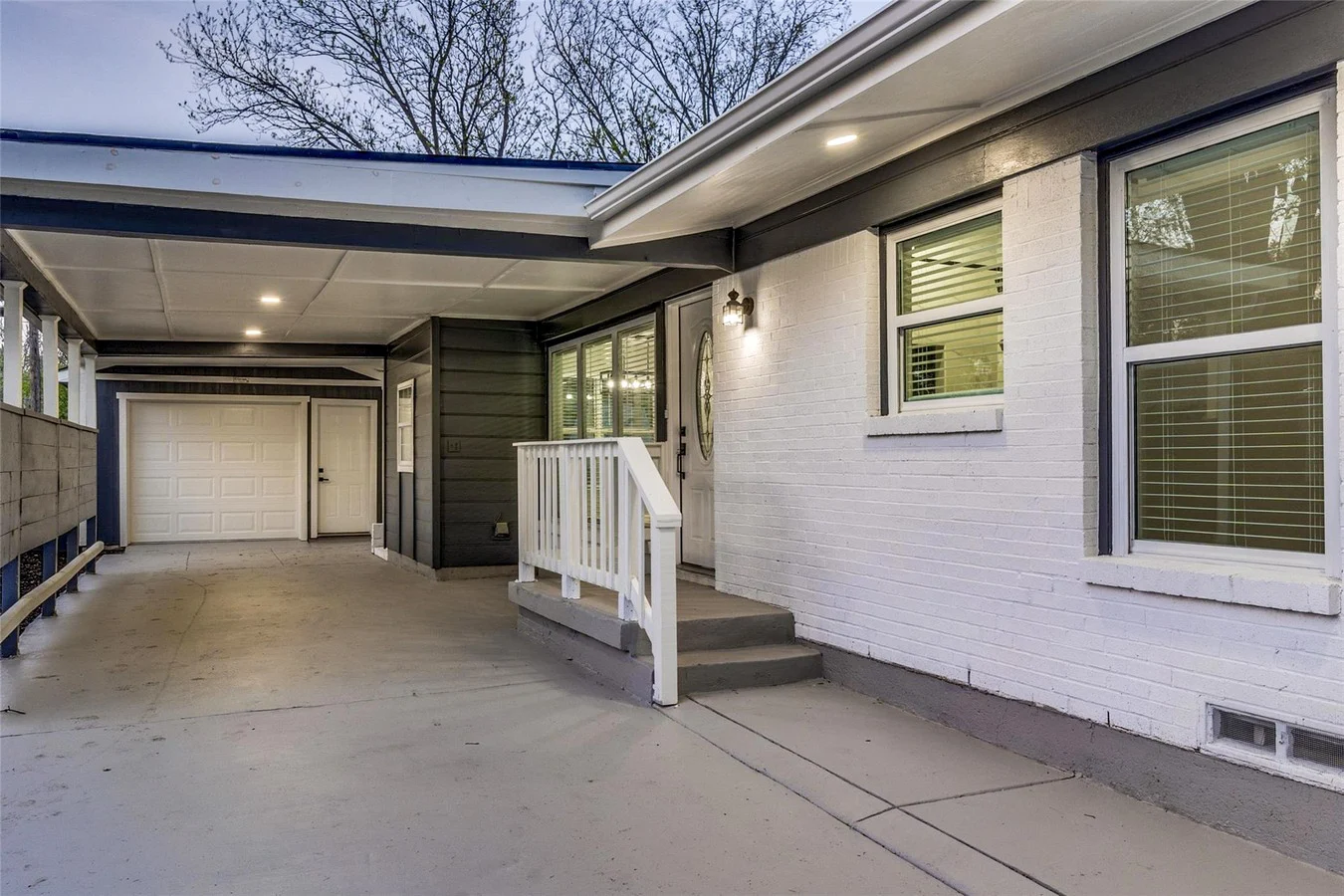 Covered carport and side entry with white brick, blue-gray siding, replacement windows, and updated exterior paint in Dallas, Texas.