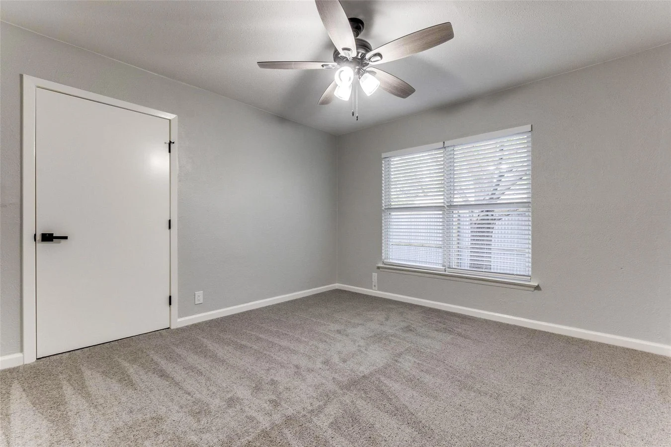 Secondary bedroom with new gray carpet, light gray walls, white trim, and a ceiling fan in Dallas, Texas.