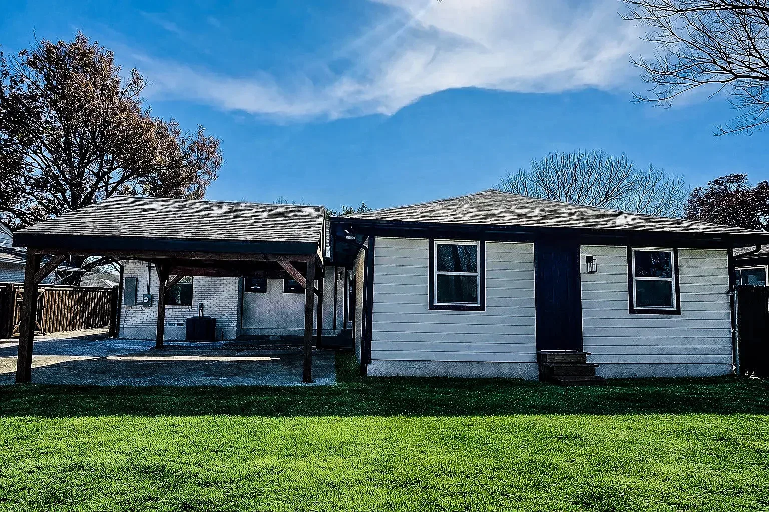 Lower Greenville home exterior with fresh light-gray paint, dark roof, covered porch, and fenced yard.