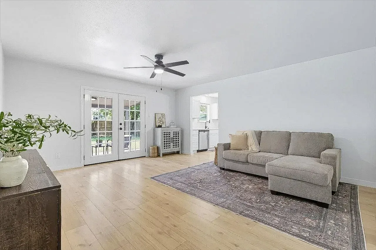 Lewisville living room with new light wood-look flooring, white walls, French doors, and staged seating.