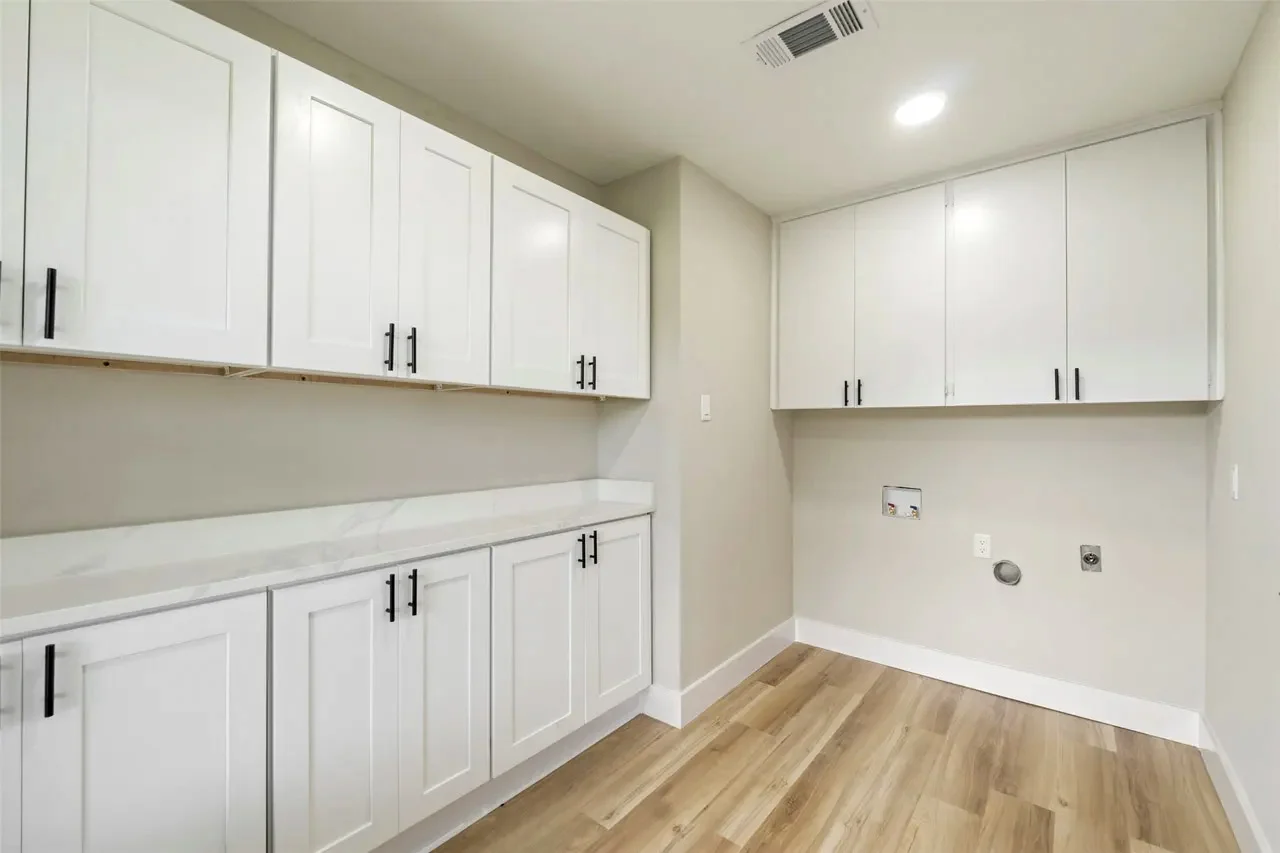 Butler pantry and utility space with white cabinetry, black hardware, stone-look counters, and wood-look flooring in Fort Worth, Texas.