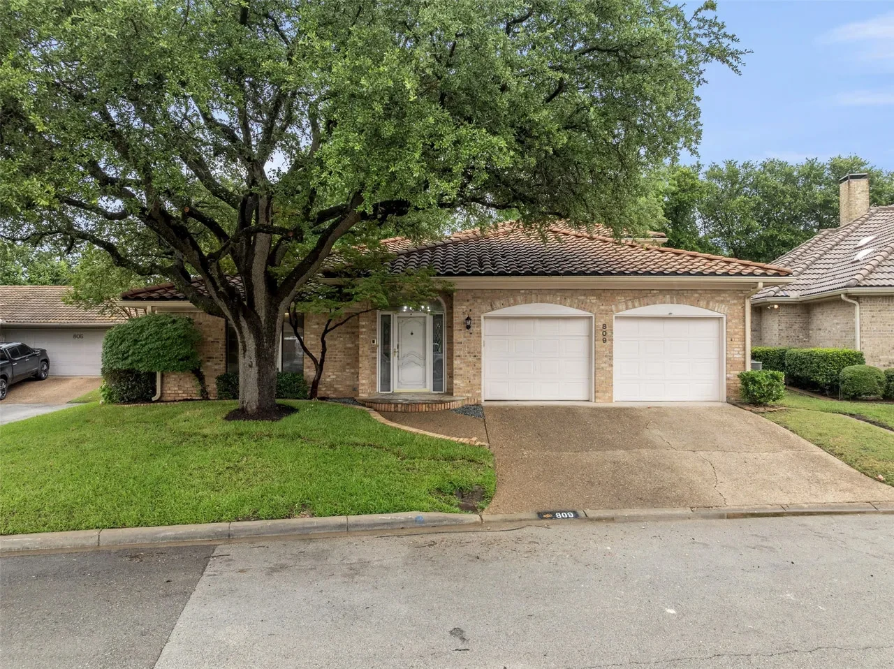 Fort Worth home exterior with brick and stucco details, a two-car garage, mature oak tree, and refreshed entry in Fort Worth, Texas.