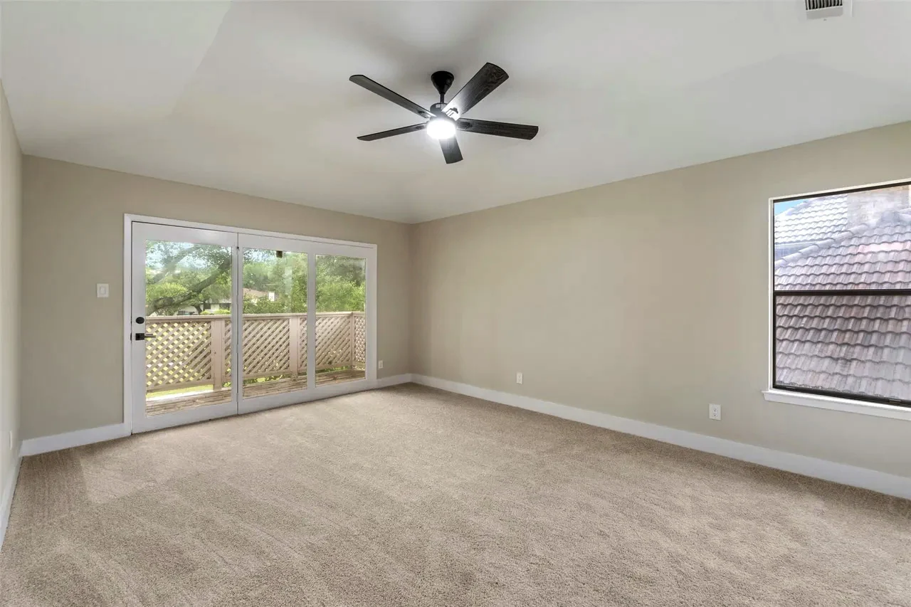 Primary suite with new carpet, neutral walls, ceiling fan, corner windows, and glass doors to the backyard in Fort Worth, Texas.