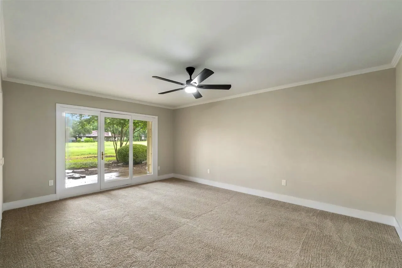 Secondary bedroom with new carpet, neutral walls, ceiling fan, and glass doors opening to the backyard in Fort Worth, Texas.