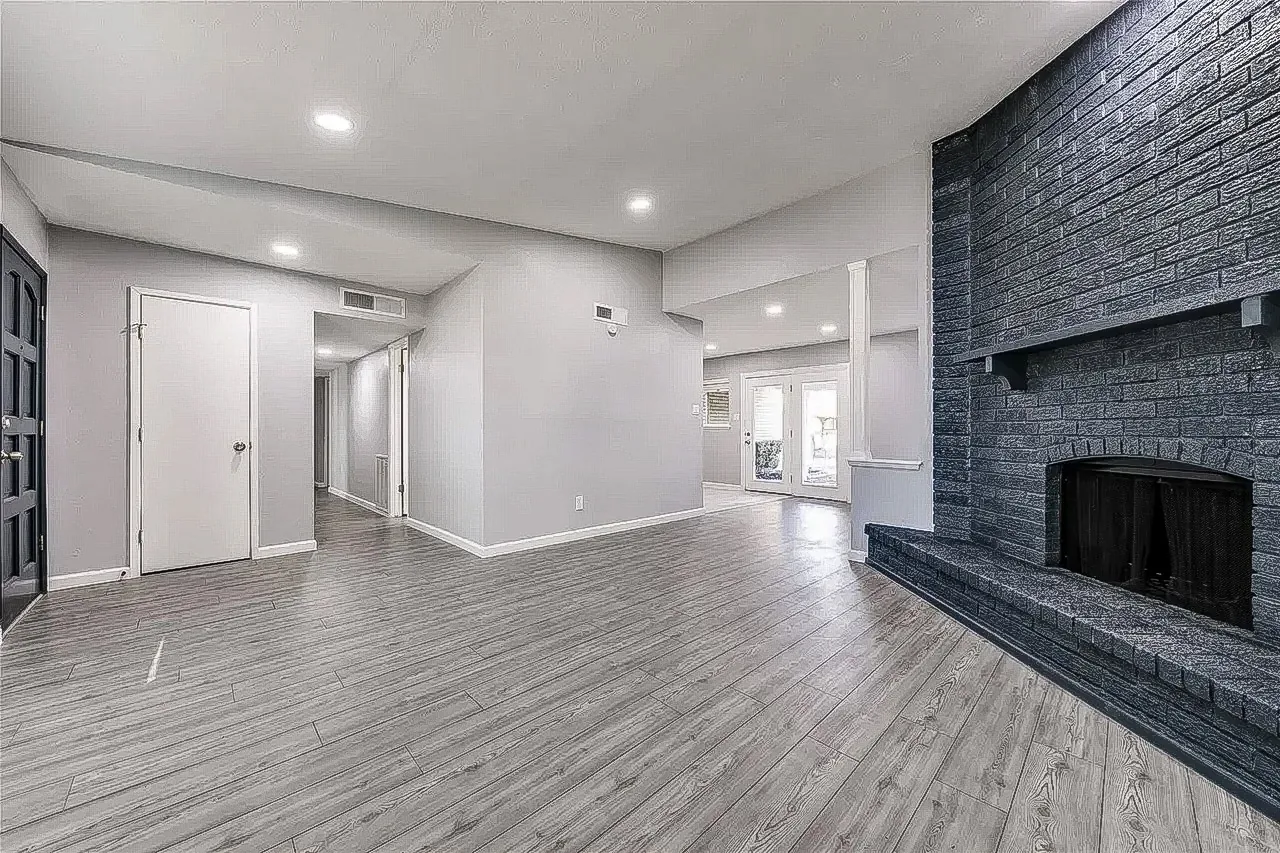 Dallas whole-home renovation with black brick fireplace, gray walls, recessed lighting, and wood-look flooring.