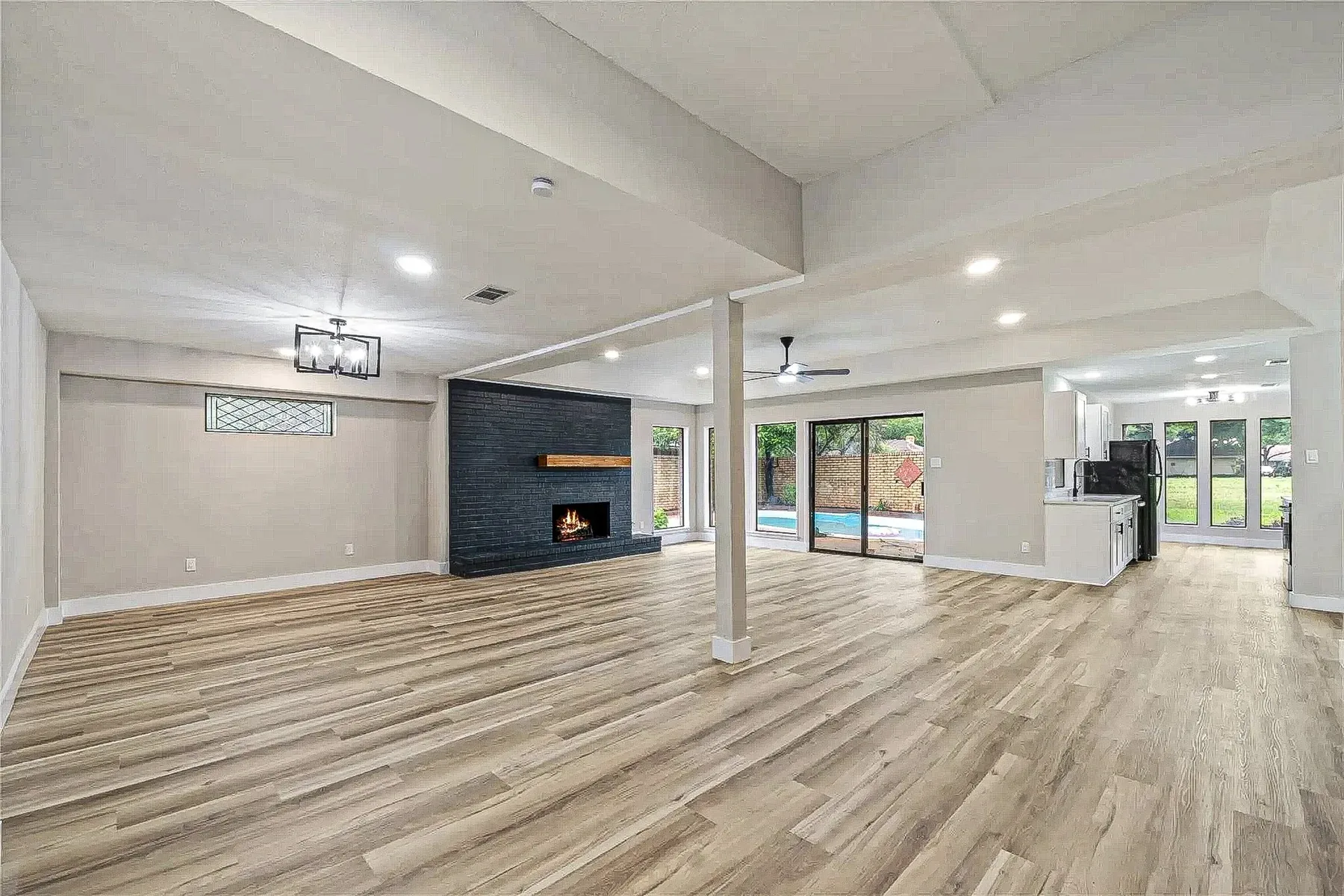 Fort Worth open living and kitchen area with black fireplace, recessed lighting, and continuous wood-look flooring.