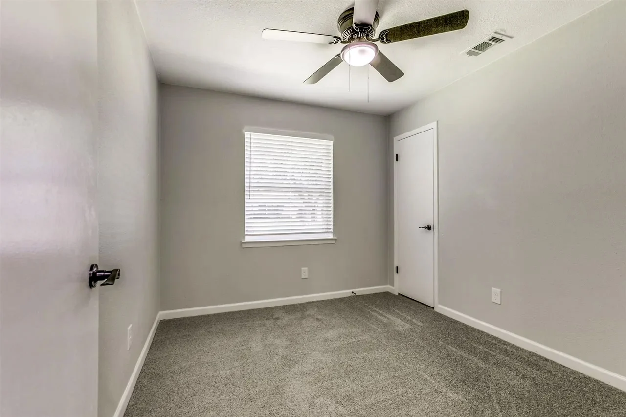 Secondary bedroom with new carpet, light gray walls, white trim, single window, and ceiling fan in Garland, Texas.