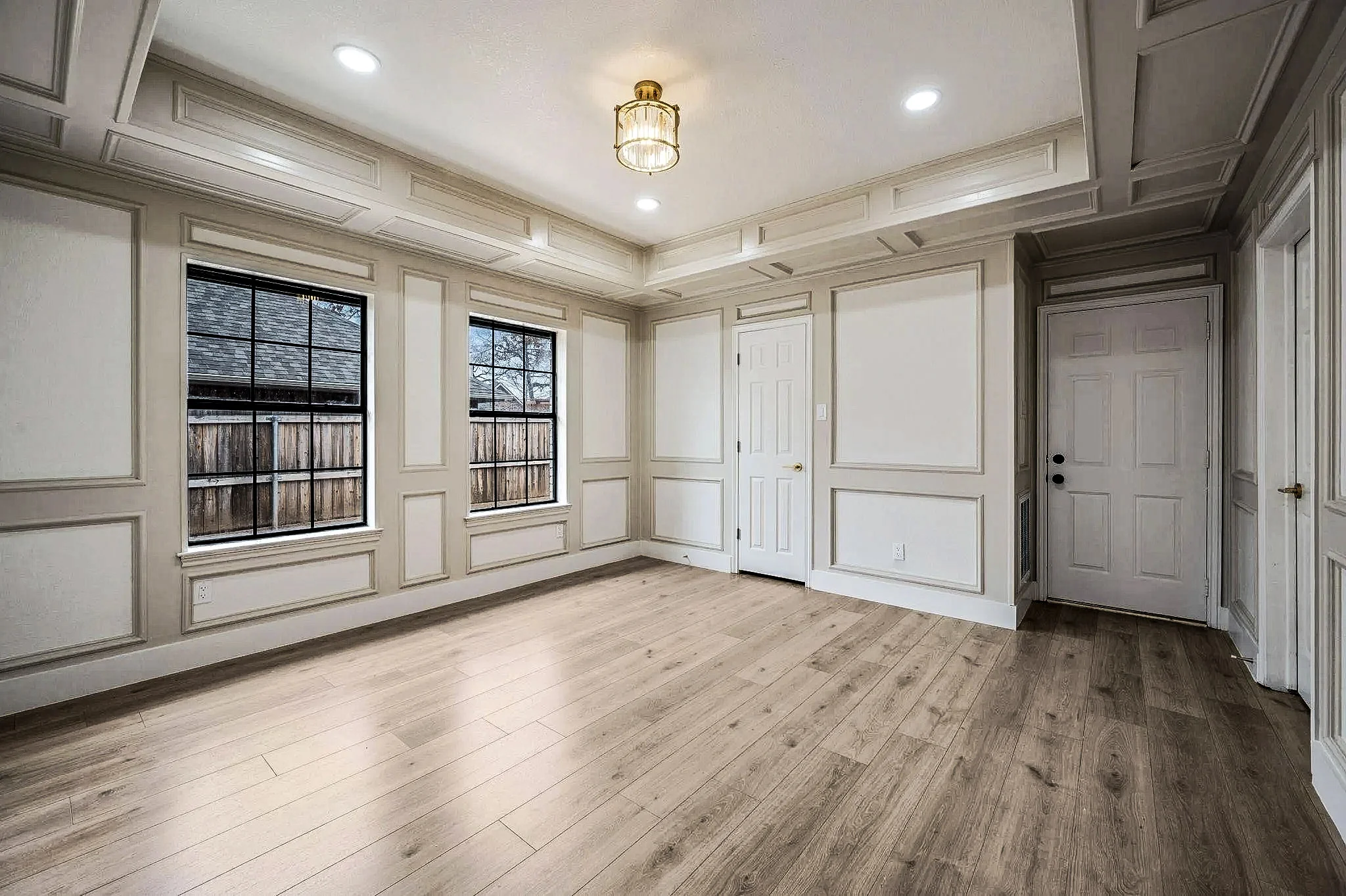 Custom library with paneled walls, built-in cabinetry, coffered ceiling details, black-framed windows, and wood-look flooring in Grapevine, Texas.