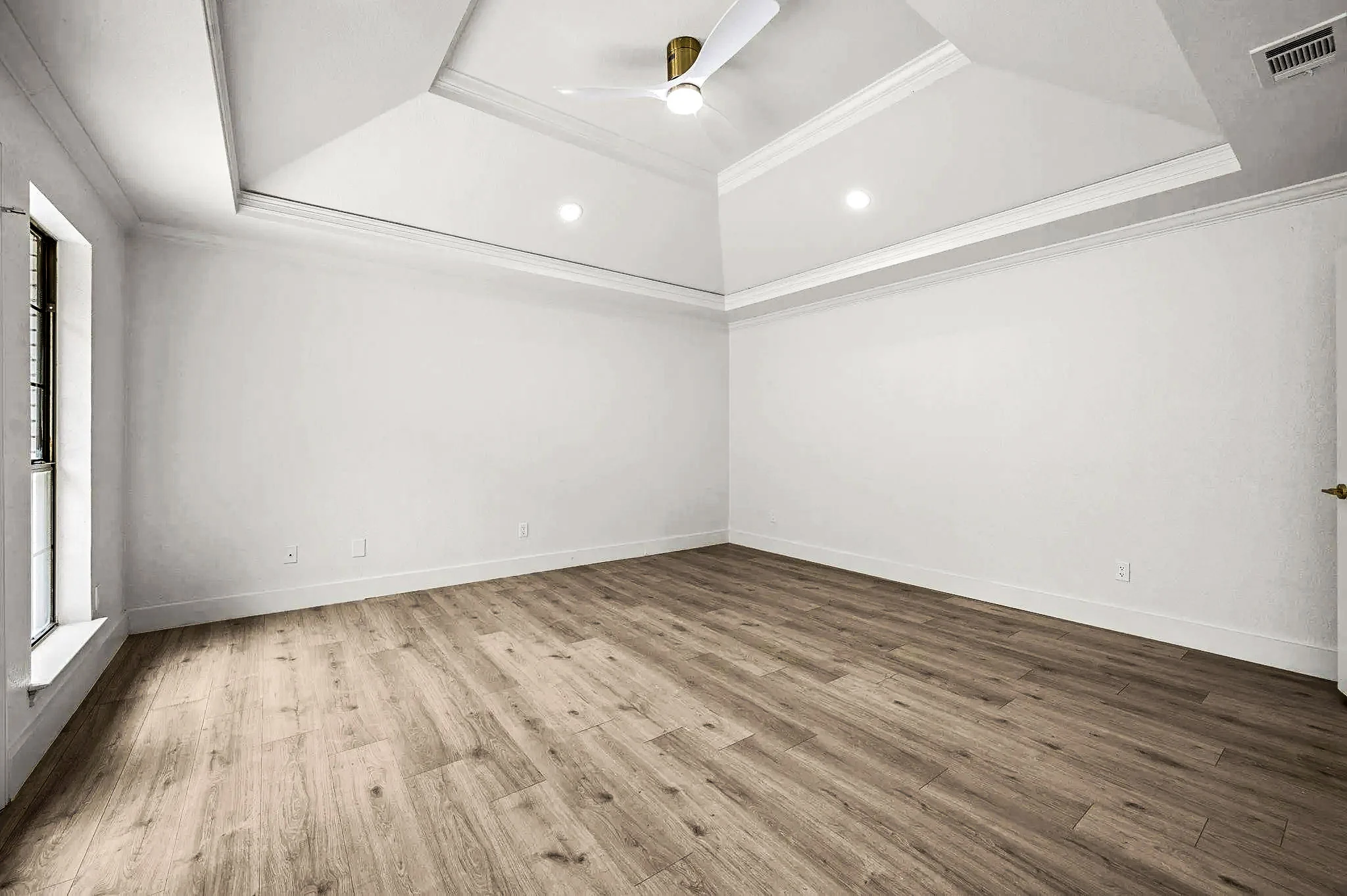 Primary bedroom with a tray ceiling, recessed lighting, black-framed windows, and wide-plank flooring in Grapevine, Texas.