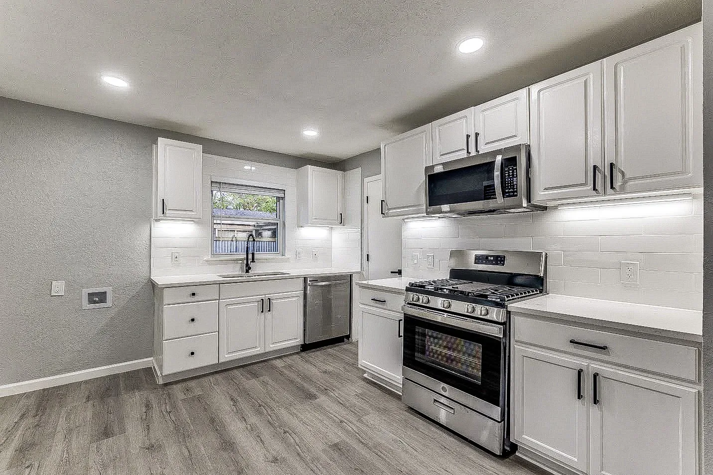 Dallas kitchen with white shaker cabinets, gray counters, stainless steel appliances, and open living area.