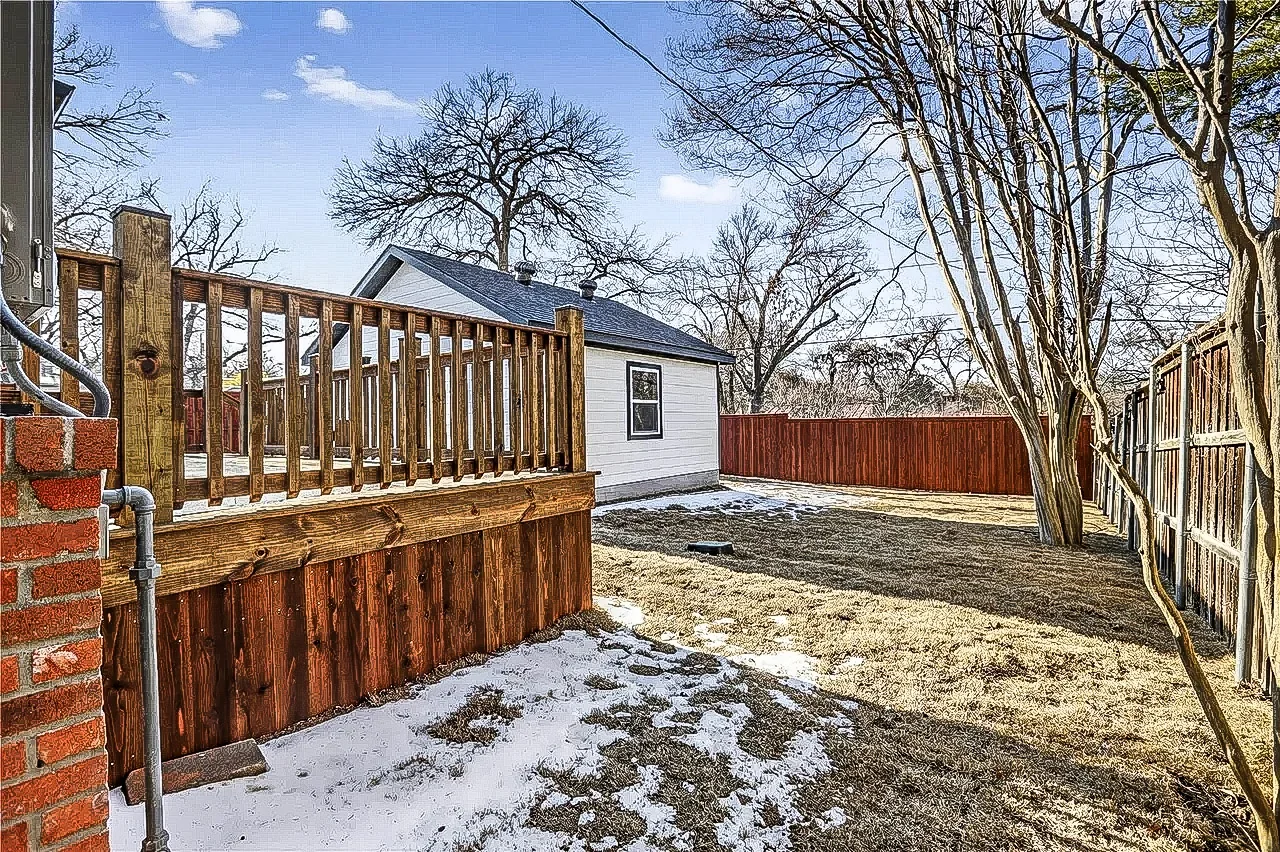 Backyard deck and accessory structure with wood railings, fenced yard, and winter landscaping in Lakewood, Dallas.