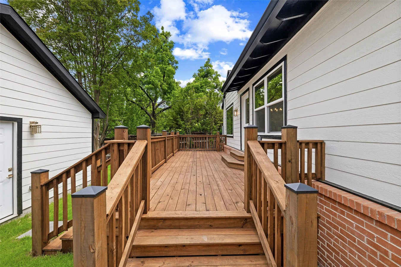 New wood deck with railings and steps connecting the Lakewood home to the detached garage and backyard in Lakewood, Dallas, Texas.