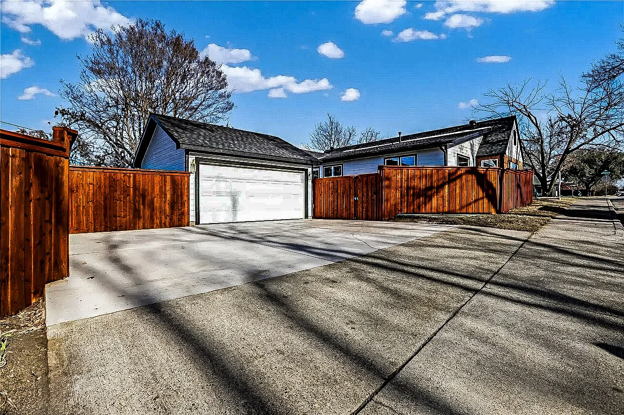 Detached garage and accessory dwelling structure with a wide concrete drive, wood privacy fencing, and coordinated exterior finishes in Lakewood, Dallas, Texas.