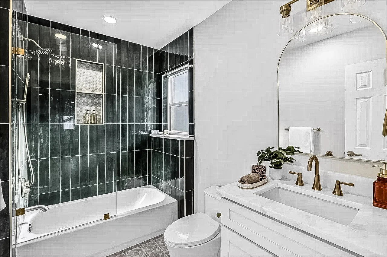 Bathroom with glossy green wall tile, white tub, rain shower, glass partition, white vanity, and brass fixtures in Lakewood, Dallas, Texas.
