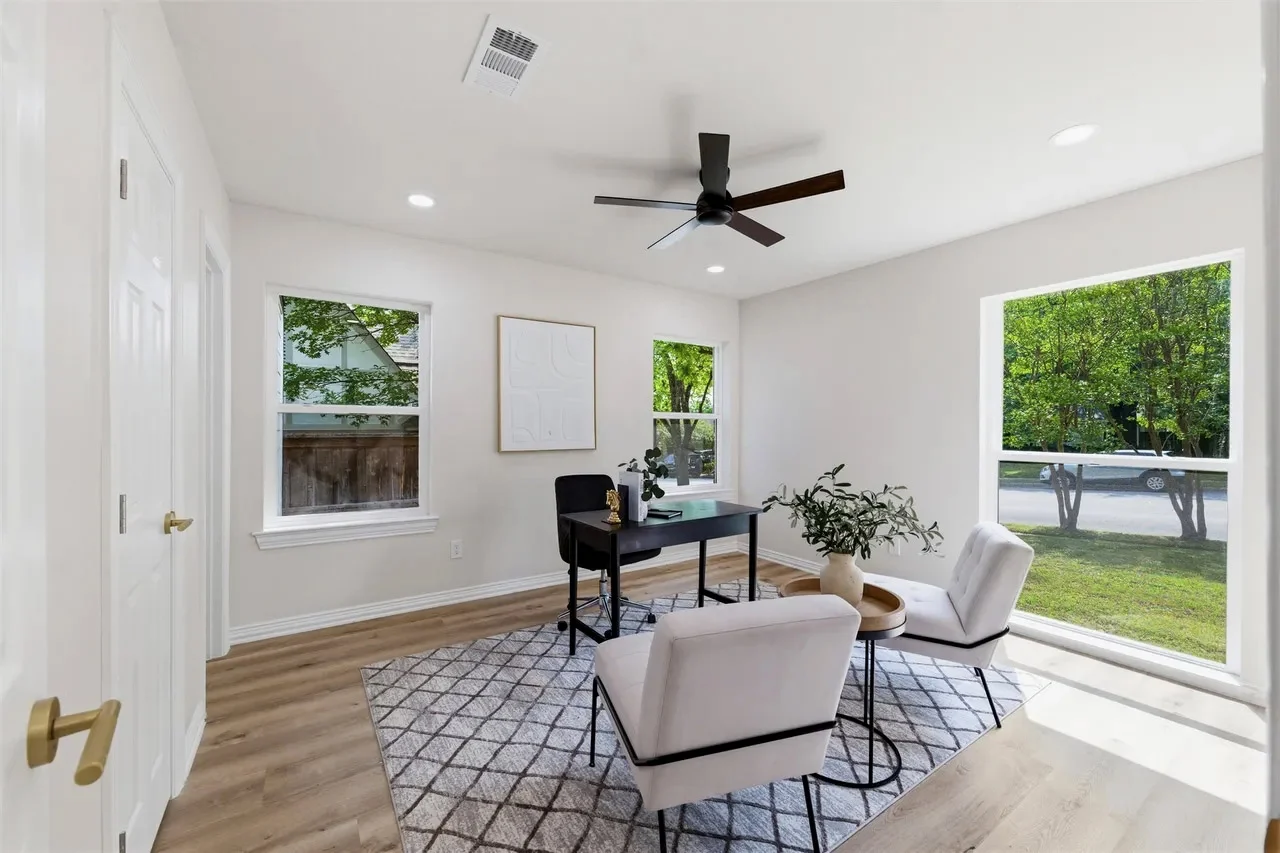 Bright home office with white walls, pale flooring, black ceiling fan, corner windows, and views across the backyard in Lakewood, Dallas, Texas.