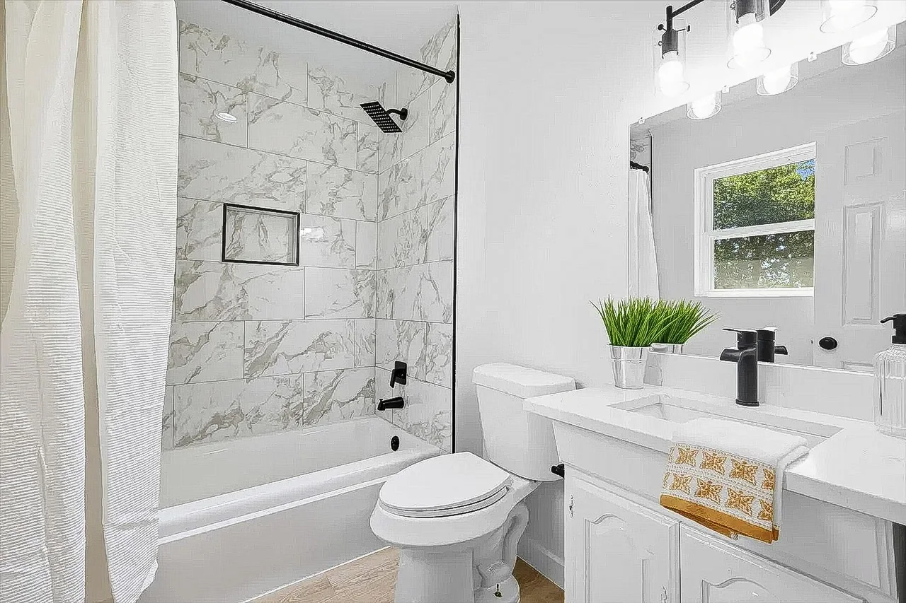 Primary bathroom with white double vanity, makeup counter, black mirrors, and glass shower in Lewisville.