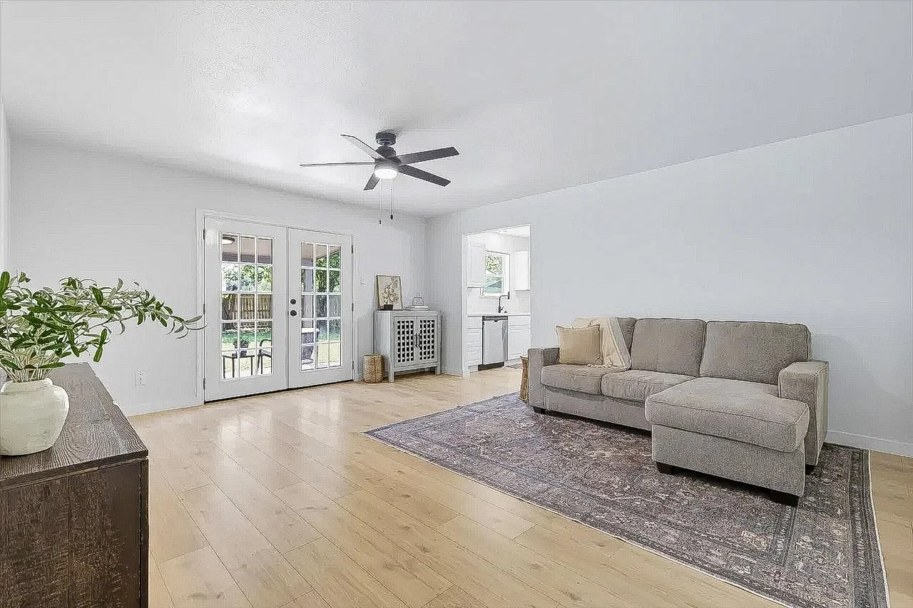Living room with new light wood-look flooring, white walls, French doors, and staged seating in Lewisville.