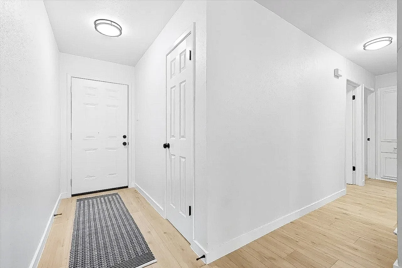 Hallway renovation with white walls, light wood-look flooring, dark hardware, and updated lighting in Lewisville.