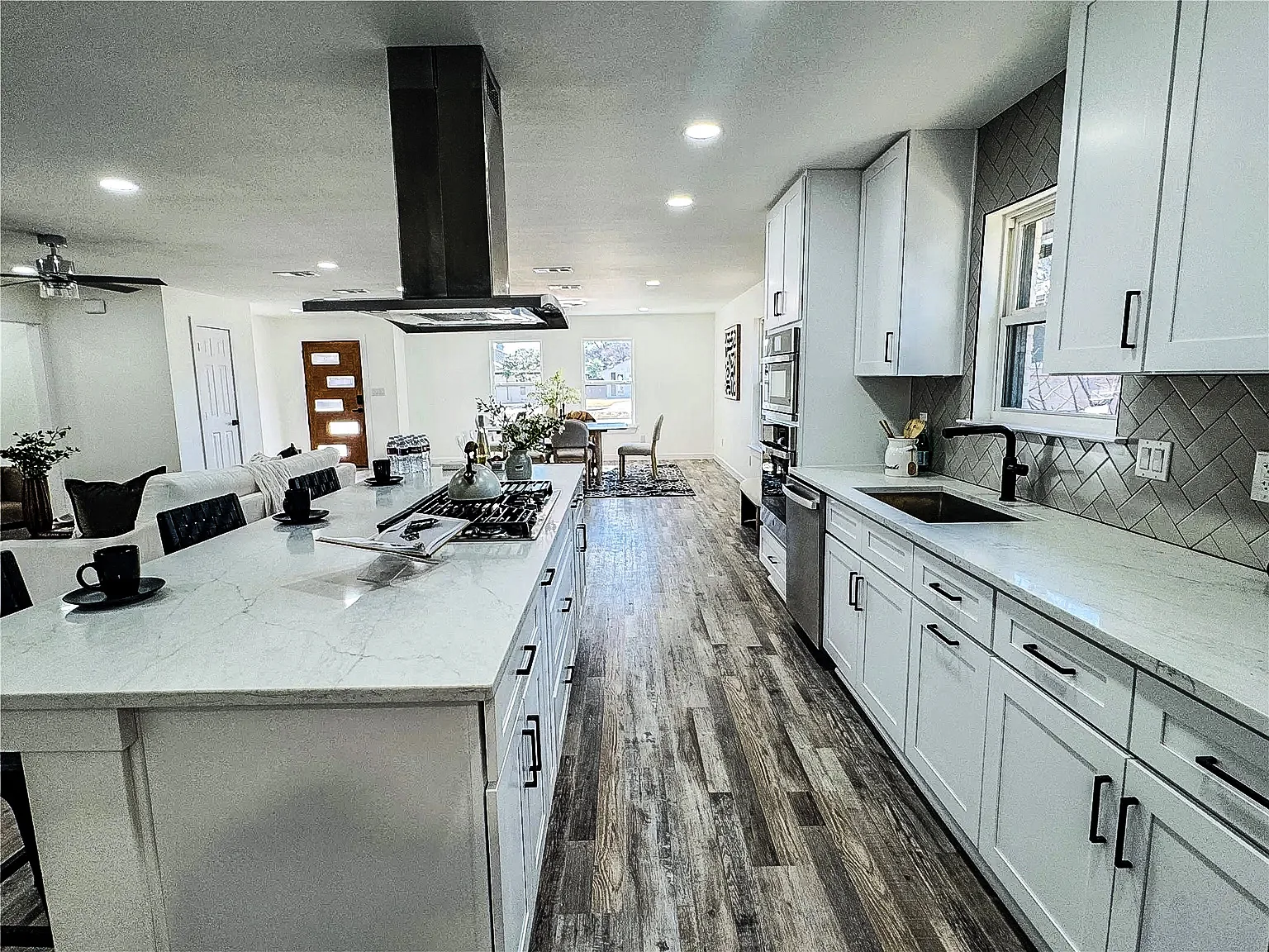 Galley kitchen with white cabinetry, black appliances, quartz counters, and black tile backsplash in Lower Greenville, Dallas.
