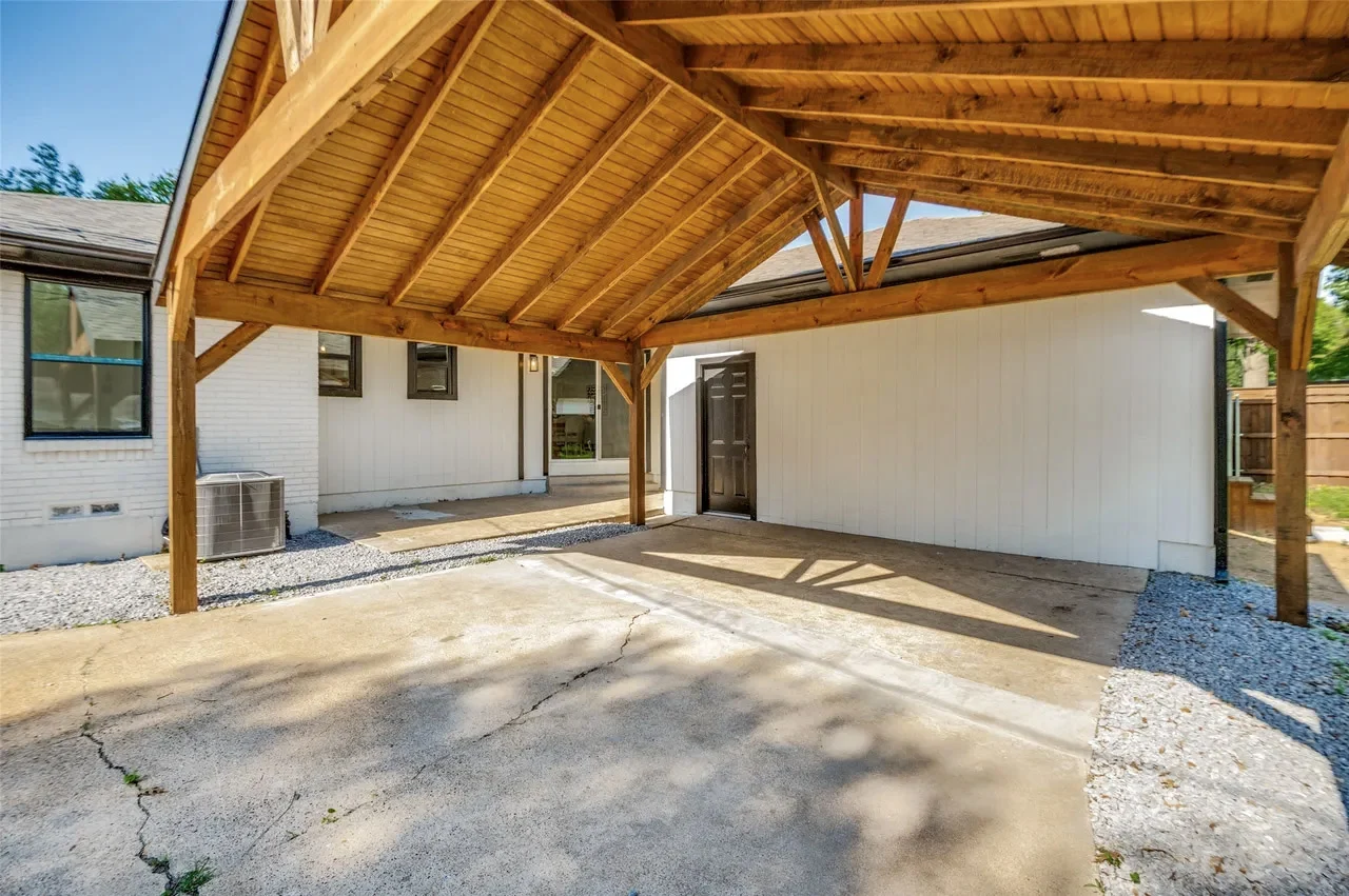 Covered outdoor structure and detached garage with repaired surfaces, fresh paint, wood ceiling framing, and concrete patio in Lower Greenville, Dallas, Texas.
