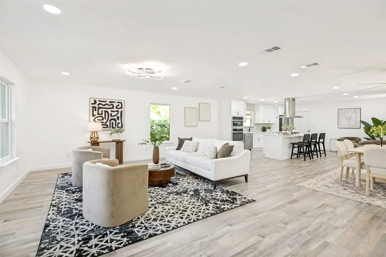 Open living, dining, and kitchen space after structural wall removal with light flooring, white walls, and staged furnishings in Lower Greenville, Dallas, Texas.
