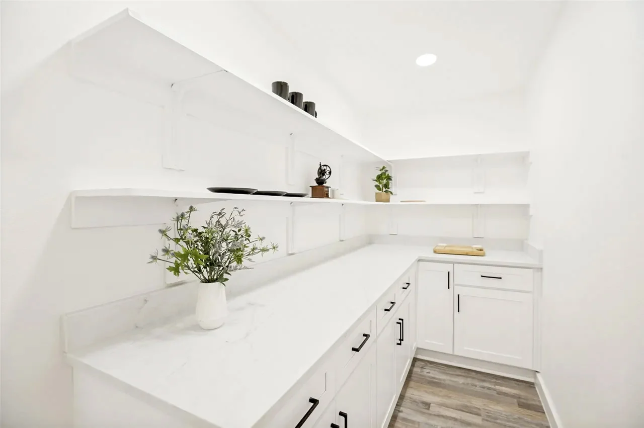 Walk-in pantry with white cabinetry, stone counters, open shelving, black hardware, and recessed lighting in Lower Greenville, Dallas, Texas.