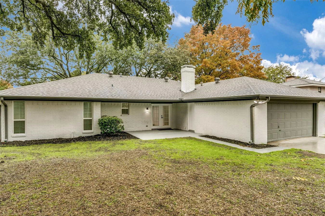 Painted single-story Plano exterior with neutral walls, dark trim, replacement windows, and a broad backyard lawn in Plano, Texas.