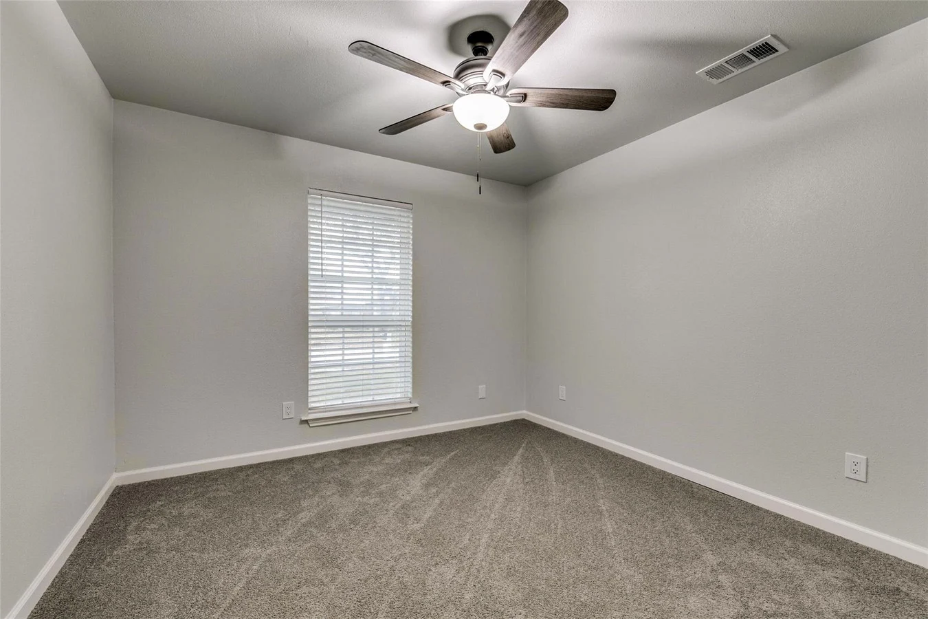 Secondary bedroom with new gray carpet, light gray walls, two windows, white trim, and ceiling fan in Plano, Texas.