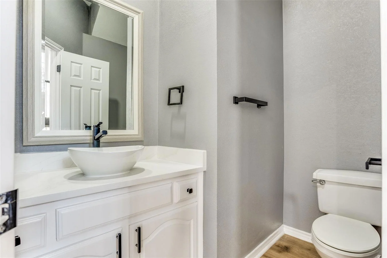 Powder room with a white vanity, vessel sink, gray walls, black fixtures, mirror, and recessed lighting in Rowlett, Texas.